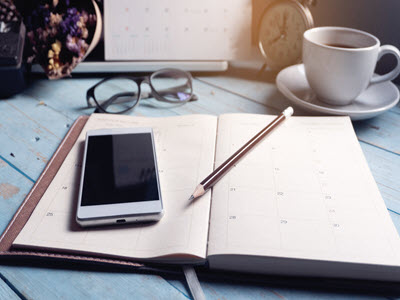 phone on planner with a cup of coffee and glasses