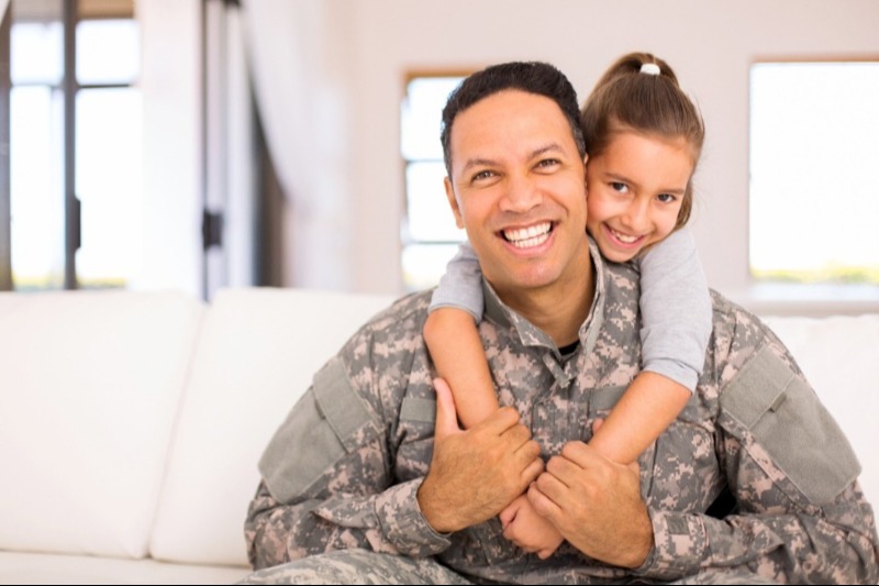 military father carrying daughter on back